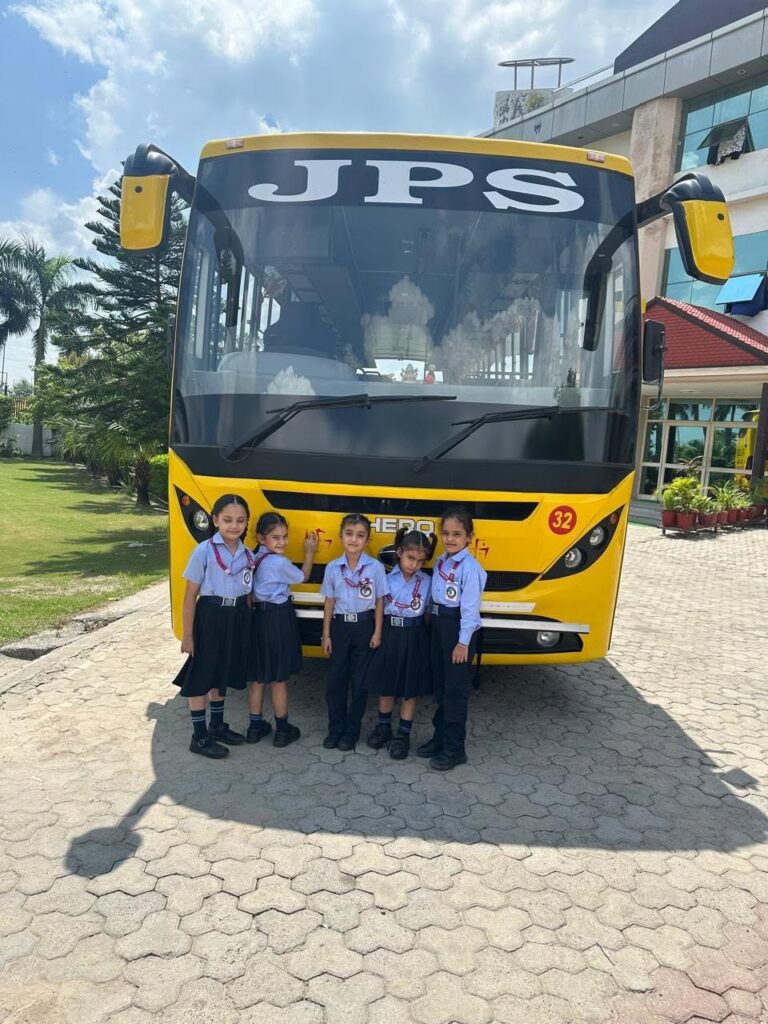 Pupils beside a JPS Academy school bus at the campus entrance
